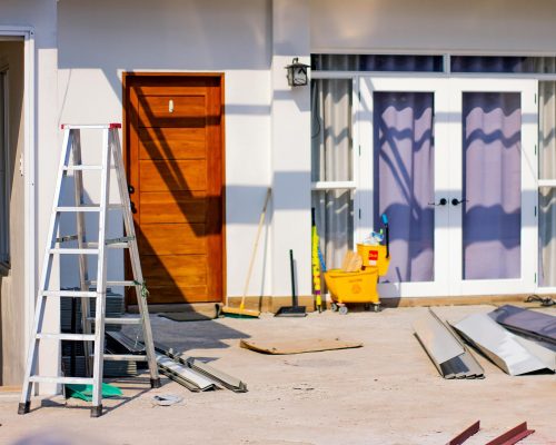 pexels-photo-4567374-4567374 Front entrance of a house under renovation with tools and materials scattered around.