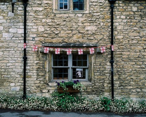 pexels-photo-941227-941227 Rustic stone facade of a traditional British house with flag bunting and flowers.
